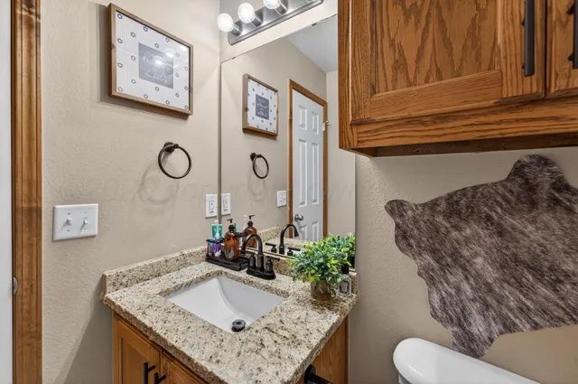 a bathroom with a granite countertop sink and a toilet