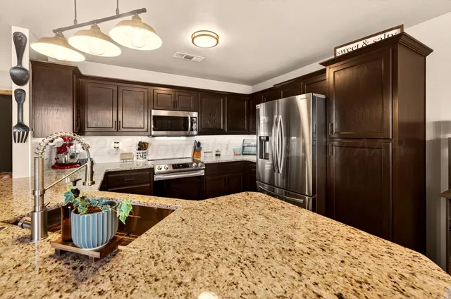 a kitchen with stainless steel appliances granite countertop a refrigerator stove and microwave