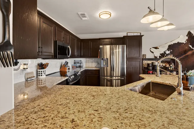 a kitchen with stainless steel appliances granite countertop a sink refrigerator and microwave
