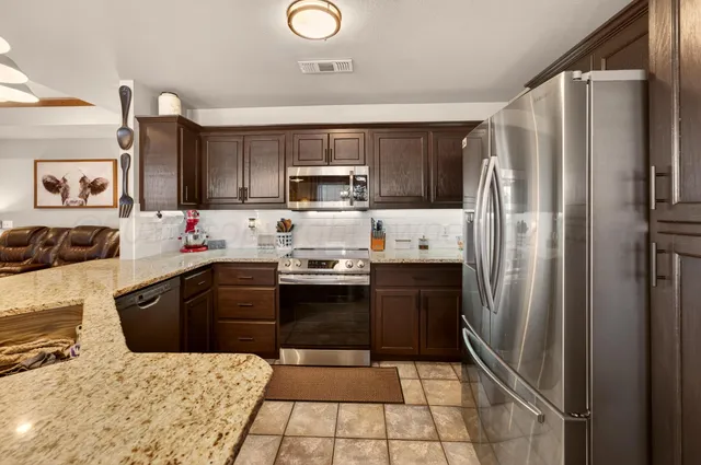 a kitchen with stainless steel appliances granite countertop a refrigerator stove top oven and sink