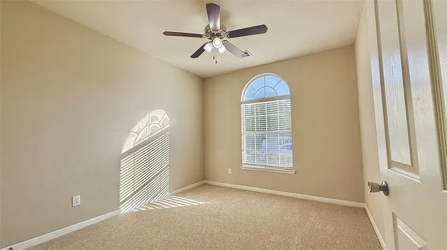 an empty room with windows and chandelier fan