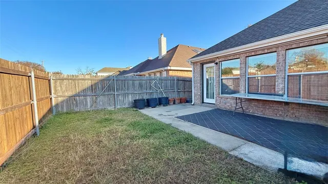 a view of a backyard with wooden fence and large trees
