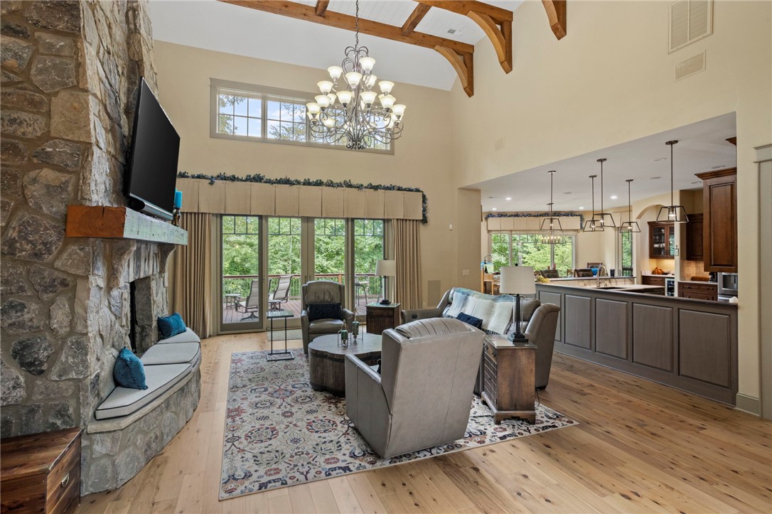 117 Sunrise Ridge Sunset, SC 29685 - Photo 4 of 44 A spacious living area featuring soaring ceilings, a striking stone fireplace, and light hardwood floors.