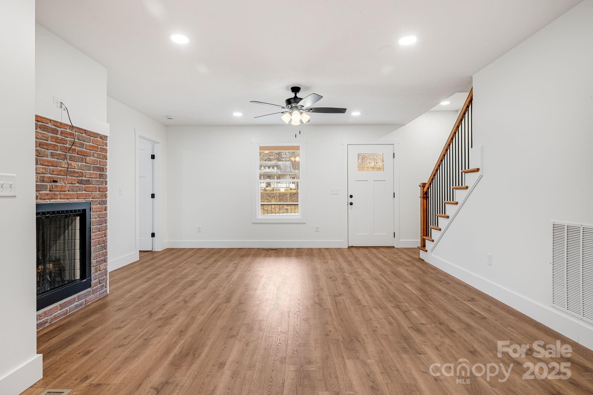 382 Holtzclaw Street Canton, NC 28716 - Photo 12 of 34 an empty room with wooden floor fireplace and windows