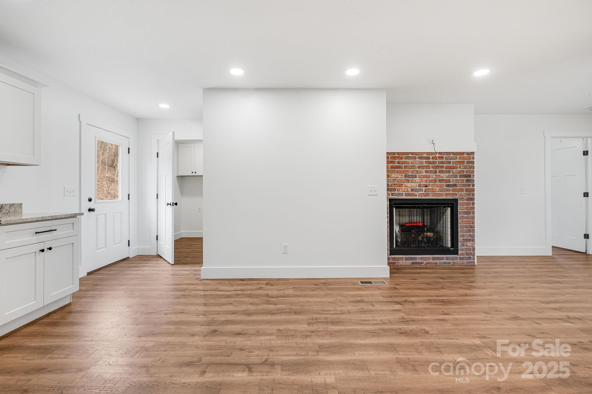 382 Holtzclaw Street Canton, NC 28716 - Photo 13 of 34 a view of an empty room with wooden floor and a kitchen