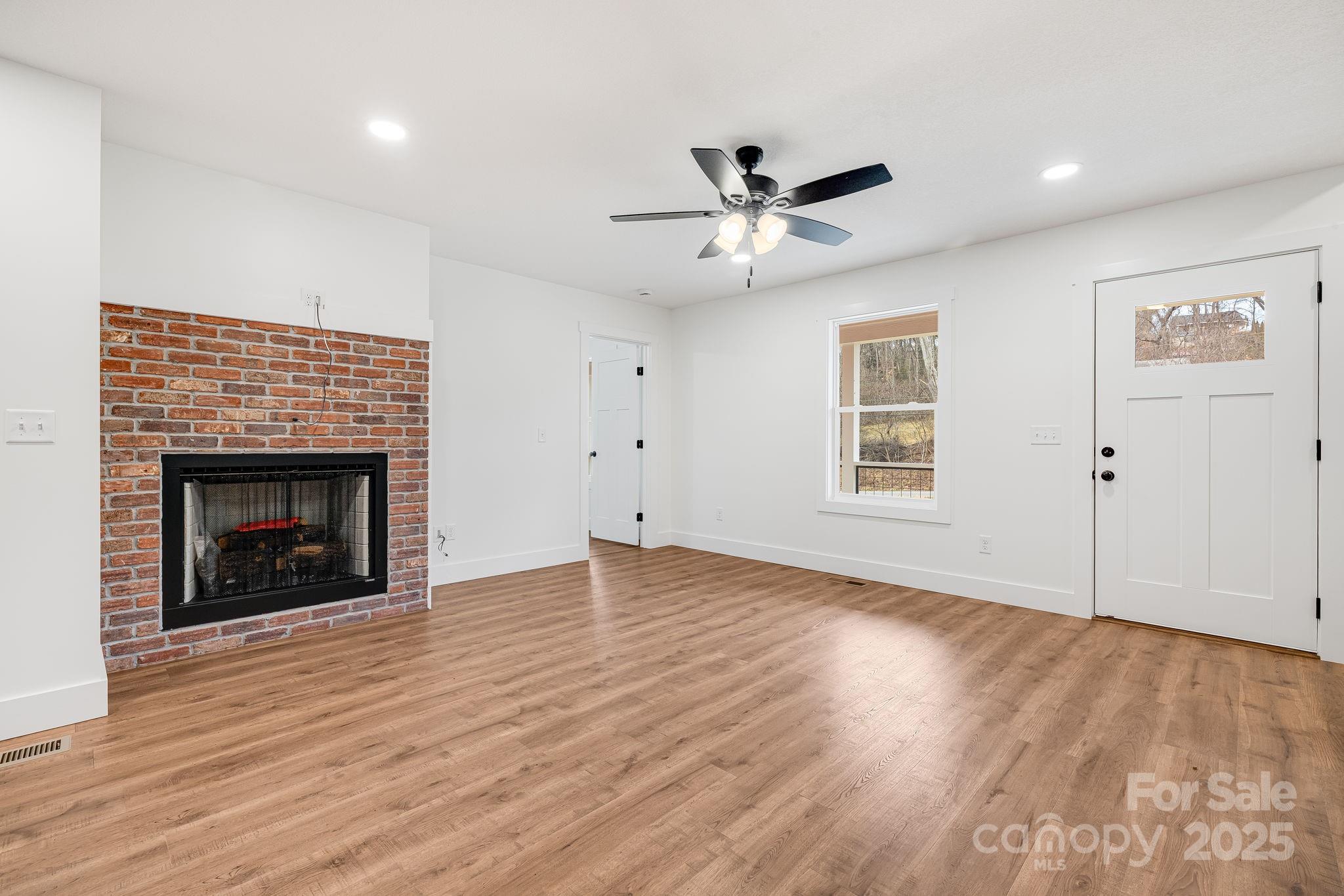382 Holtzclaw Street Canton, NC 28716 - Photo 10 of 34 a view of empty room with wooden floor and fireplace