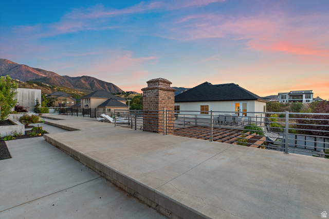 912 North Loafer Canyon Road Elk Ridge, UT 84651 - Photo 82 of 98 Expansive concrete patio with integrated planters, a brick chimney feature, and metal railings overlooking mountain scenery