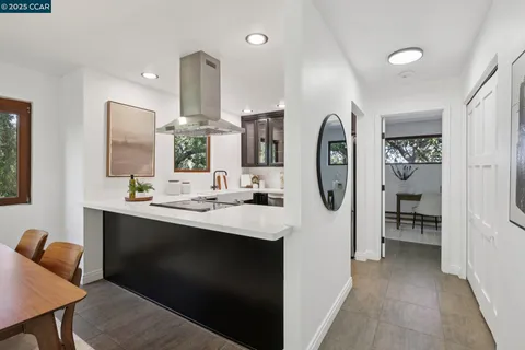 a view of a kitchen with kitchen island a large window cabinets a sink and stainless steel appliances