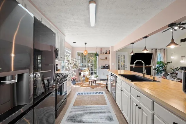 a view of a kitchen with kitchen island a large counter top space a sink stainless steel appliances and cabinets