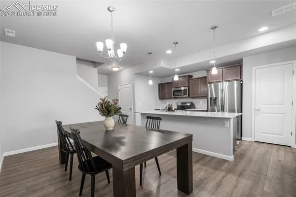 a kitchen with a dining table chairs stainless steel appliances and cabinets