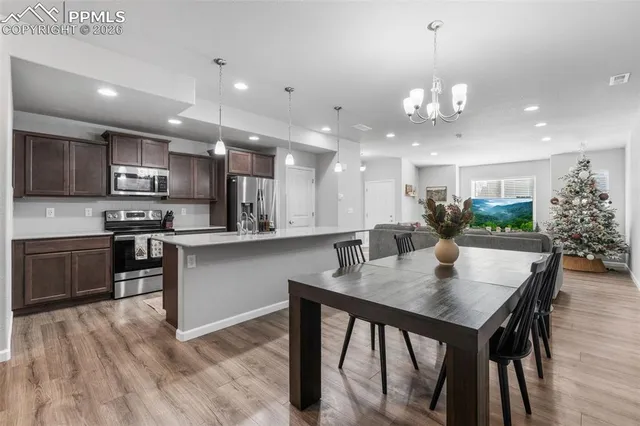 a kitchen with a dining table chairs stainless steel appliances and cabinets