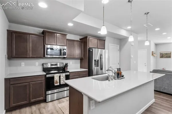 a kitchen with stainless steel appliances a sink a stove a microwave a refrigerator a center island and cabinets