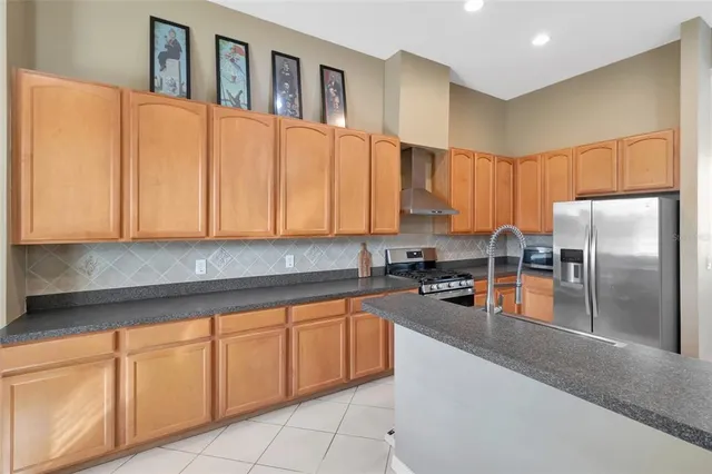 a kitchen with stainless steel appliances granite countertop a refrigerator a sink a stove with wooden cabinets
