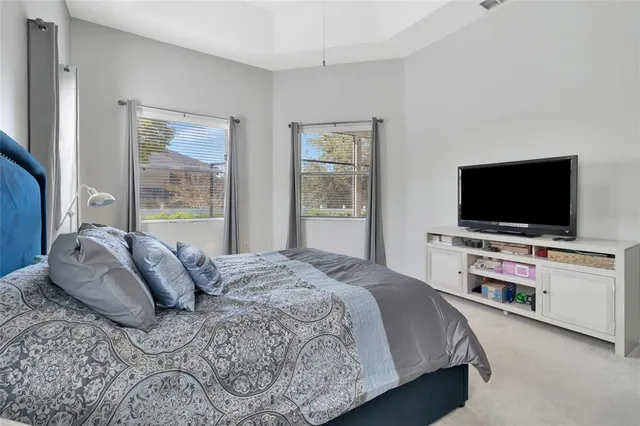 a bedroom with a bed and a flat tv screen on the dresser