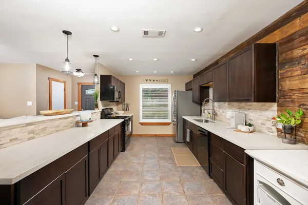 a large kitchen with a large counter top a sink stainless steel appliances and cabinets