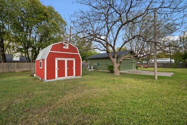 a view of a yard in front of a house with a large tree