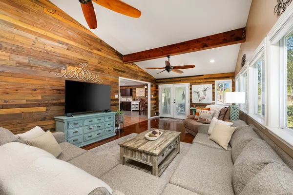 a living room with furniture a flat screen tv and a floor to ceiling window