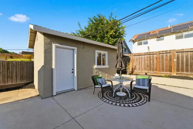 a view of a patio with table and chairs and wooden fence