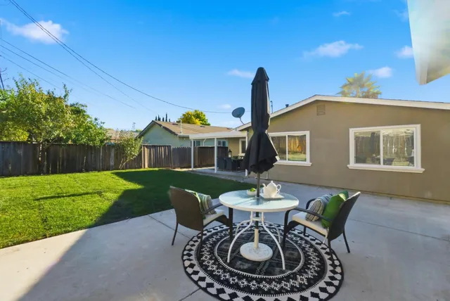 a view of a house with backyard sitting area and a garden