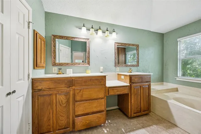 a bathroom with a double vanity sink mirror and bathtub