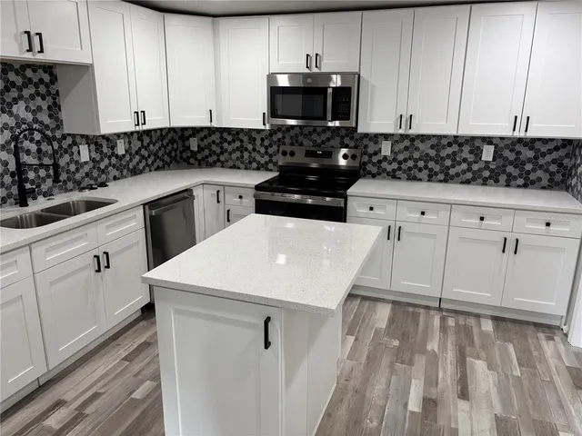 a kitchen with white cabinets sink and stainless steel appliances