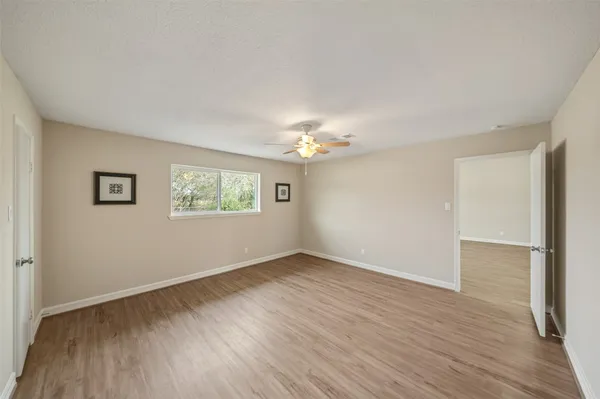 an empty room with wooden floor chandelier and windows