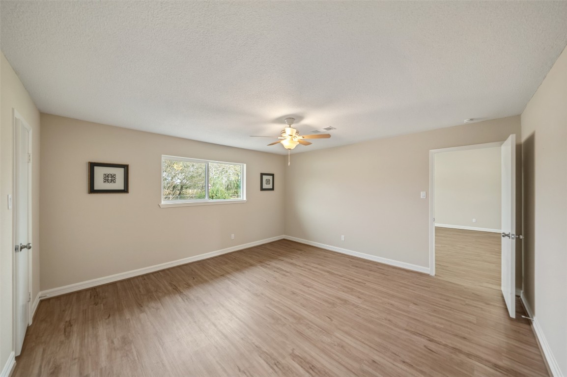 355 Windsor Square Alvin, TX 77511 - Photo 11 of 22 This spacious room features light wood flooring, neutral walls, a ceiling fan, and ample natural light from a large window. It connects to an adjacent room, offering versatile living space.