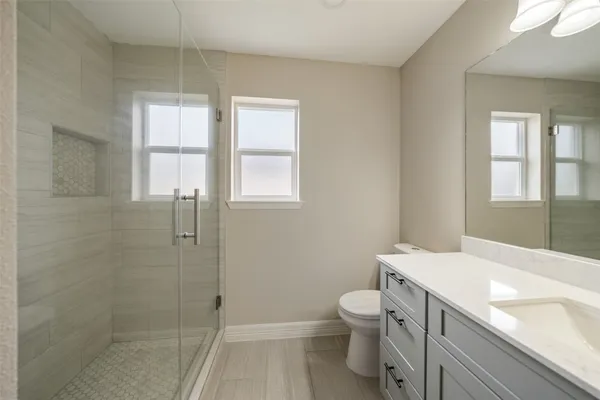 a bathroom with a granite countertop toilet a sink and a shower
