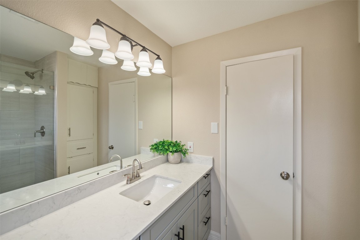 355 Windsor Square Alvin, TX 77511 - Photo 14 of 22 This bathroom features a modern design with a sleek vanity and ample countertop space. It includes a large mirror with overhead lighting, a built-in shower with a glass door, and neutral-toned walls for a clean, fresh look.