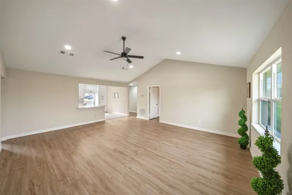 a view of an empty room with a window and wooden floor