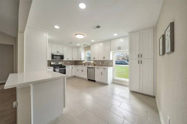 a large kitchen with cabinets and stainless steel appliances