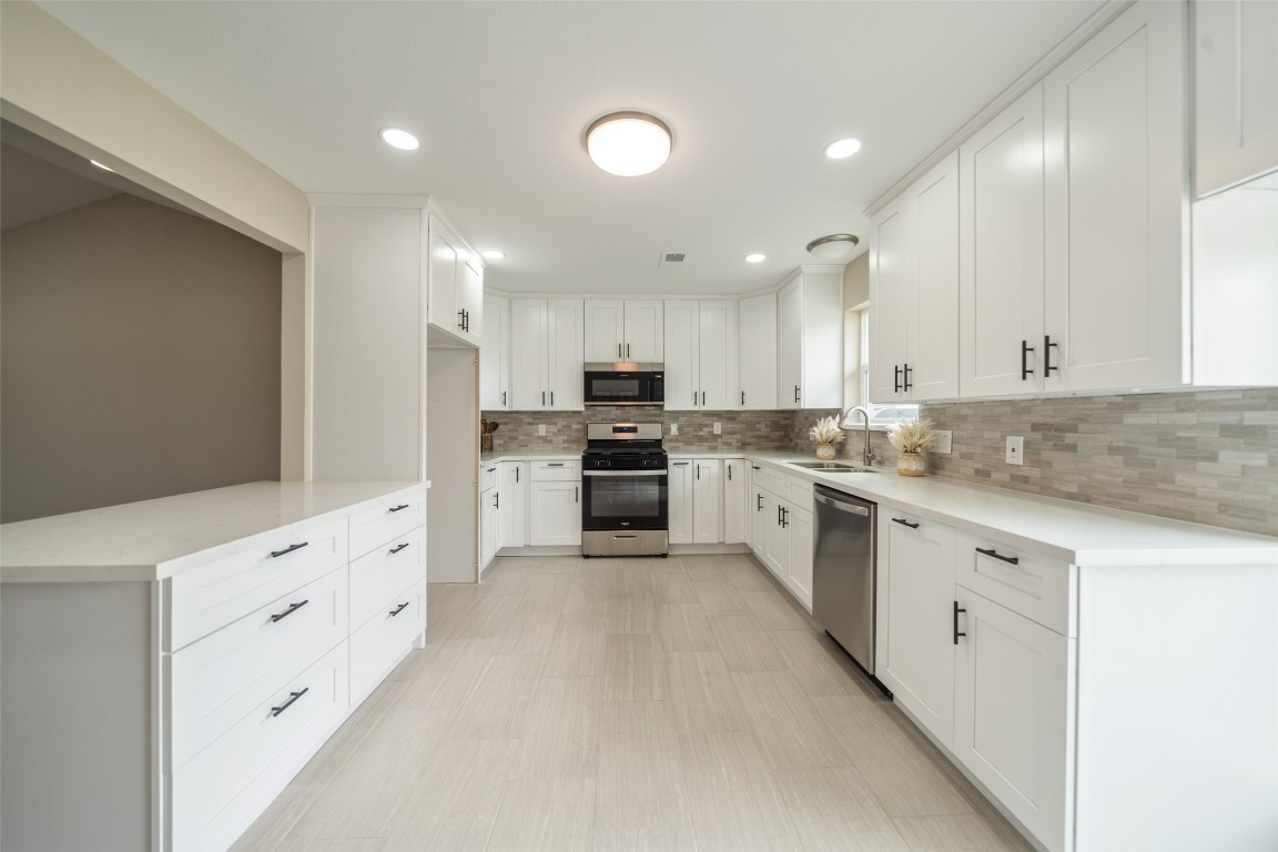 355 Windsor Square Alvin, TX 77511 - Photo 6 of 22 A modern kitchen with white cabinetry, stainless steel appliances, and a neutral backsplash. The room is bright and spacious, featuring ample counter space and recessed lighting.