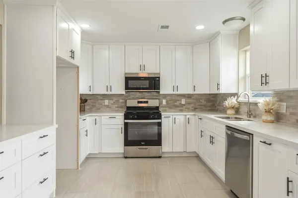 a kitchen with granite countertop white cabinets and stainless steel appliances