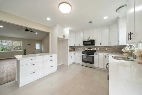 a kitchen with granite countertop white cabinets and stainless steel appliances