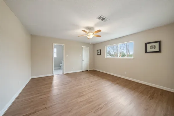 a view of an empty room with a window and wooden floor