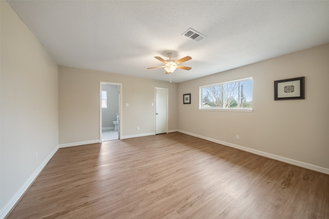 355 Windsor Square Alvin, TX 77511 - Photo 10 of 22 This spacious bedroom features light wood flooring, neutral walls, and ample natural light from a large window. It includes a ceiling fan and an en-suite bathroom for added convenience.