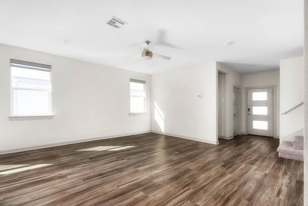 an empty room with wooden floor and windows