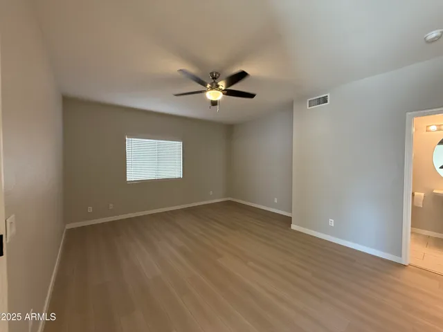 an empty room with wooden floor fan and windows