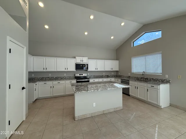 a kitchen with stainless steel appliances granite countertop a stove top oven a sink a refrigerator and a granite counter tops