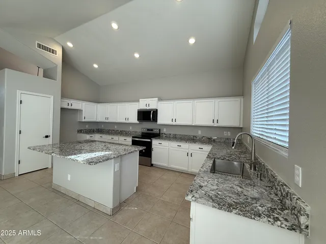 a kitchen with granite countertop a sink stove top oven and cabinets
