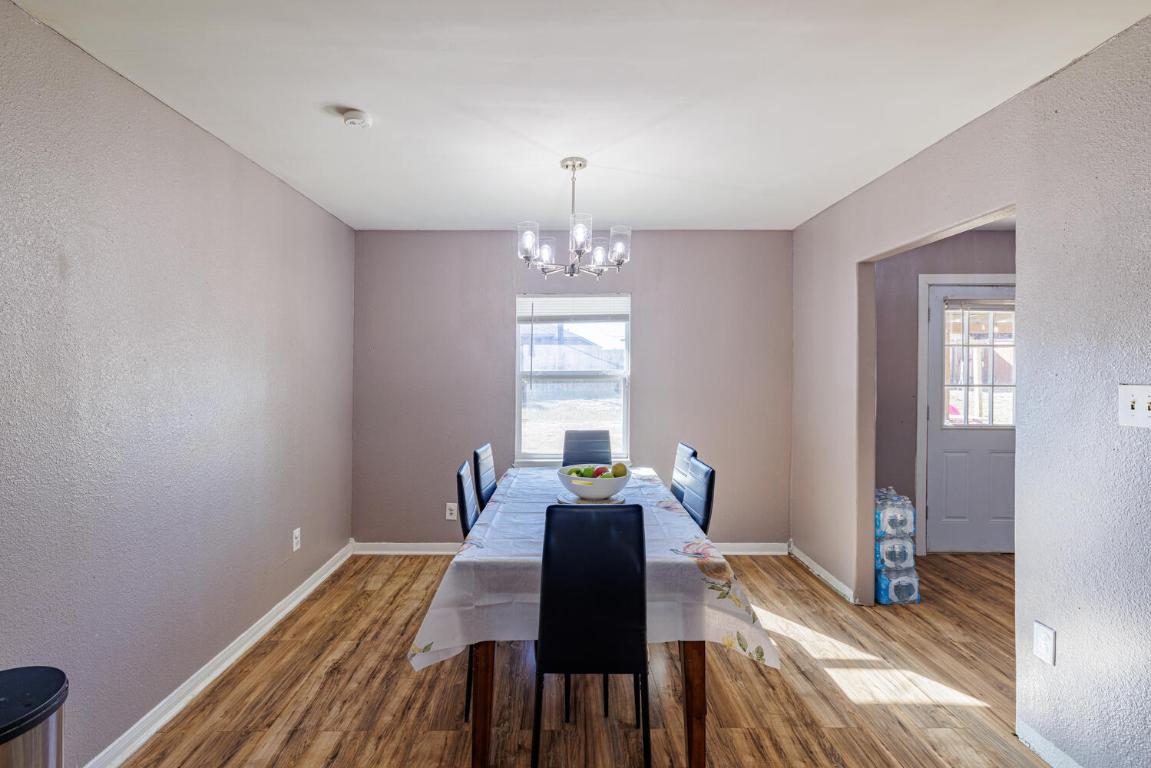 112 Maynard Street Bastrop, TX 78602 - Photo 13 of 35 Dining room featuring a textured wall, wood finished floors, and a chandelier