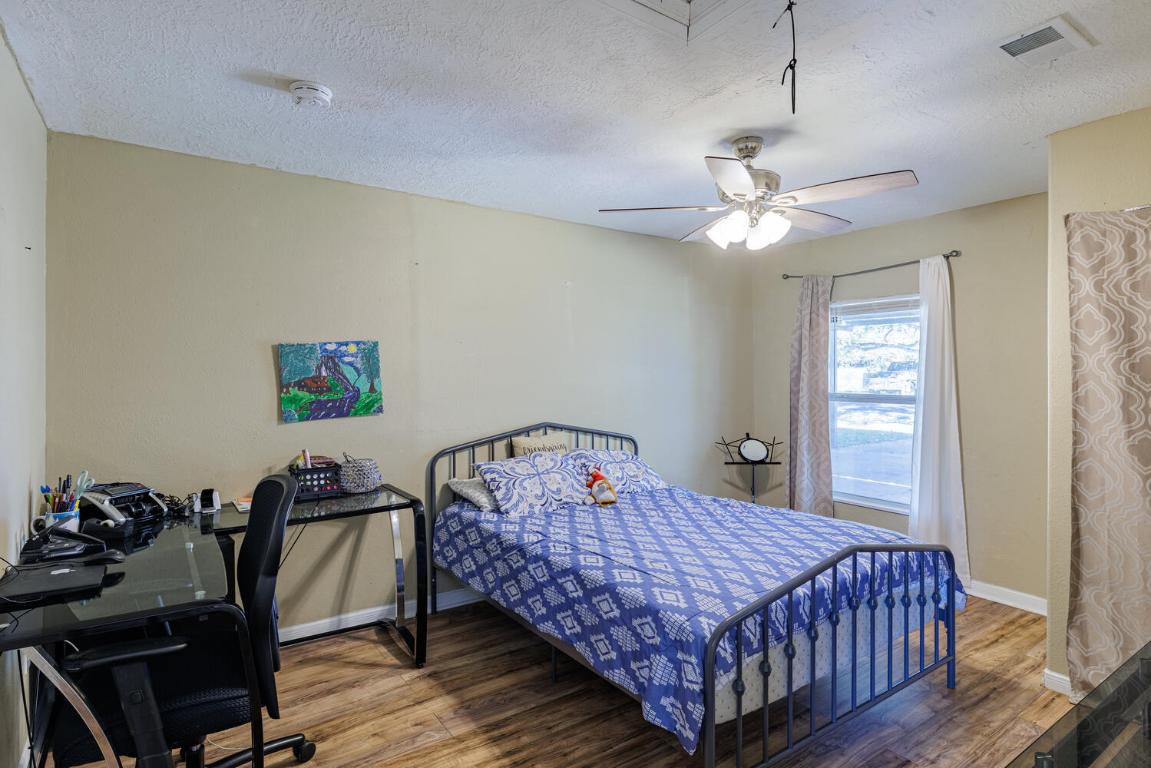 112 Maynard Street Bastrop, TX 78602 - Photo 19 of 35 Bedroom featuring wood finished floors, a textured ceiling, ceiling fan, an office area, and attic access