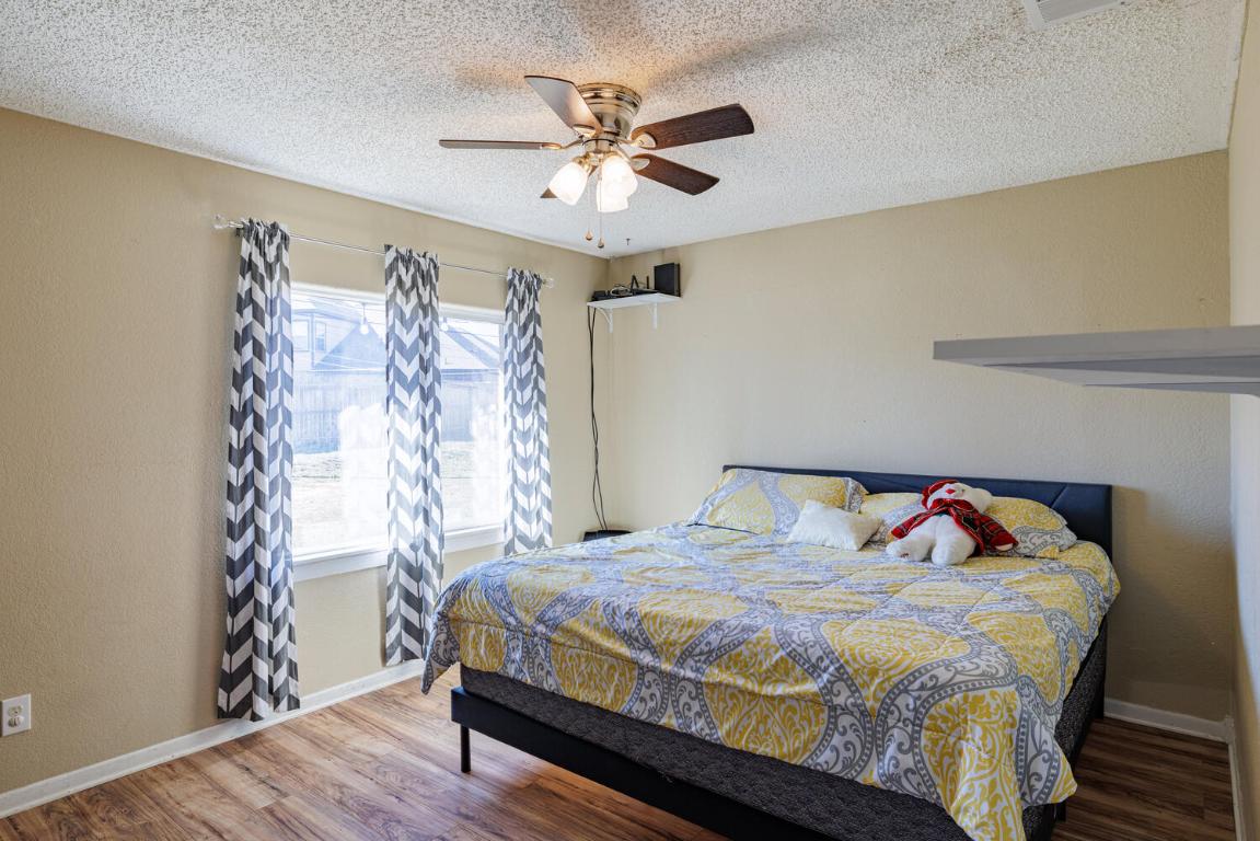 112 Maynard Street Bastrop, TX 78602 - Photo 21 of 35 Bedroom with wood finished floors, ceiling fan, a textured ceiling, and a textured wall