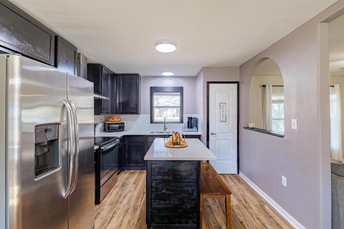 112 Maynard Street Bastrop, TX 78602 - Photo 10 of 35 Kitchen featuring stainless steel appliances, a kitchen island, light wood-style floors, decorative backsplash, and a kitchen breakfast bar