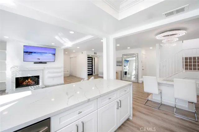 a large white kitchen with a fireplace and a large window