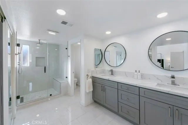 a bathroom with a double vanity sink toilet and shower