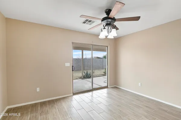 an empty room with wooden floor fan and windows