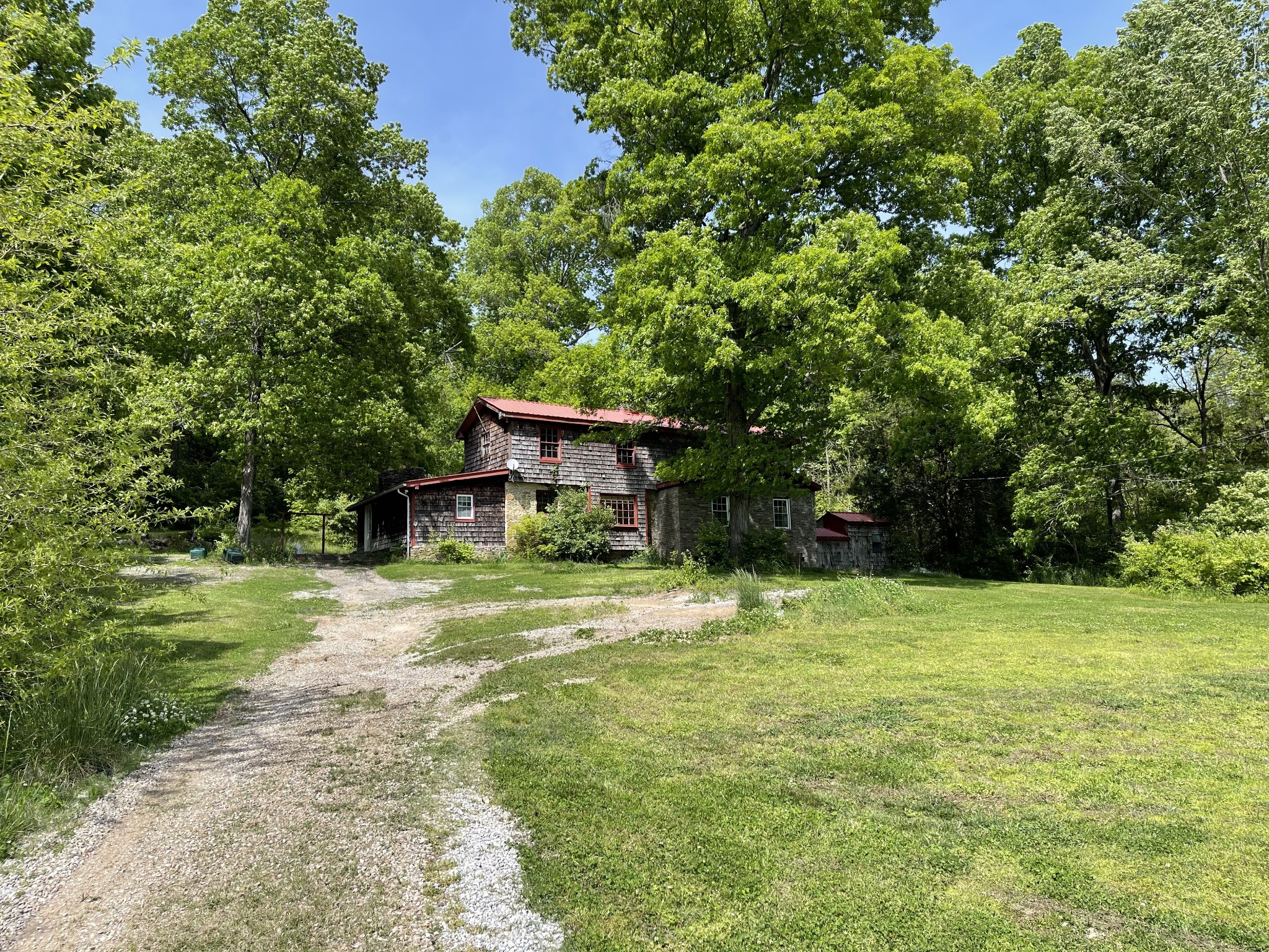 4392 North Chapel Road Franklin, TN 37067 - Photo 1 of 9 a yellow house in middle of a yard with potted plants and large trees