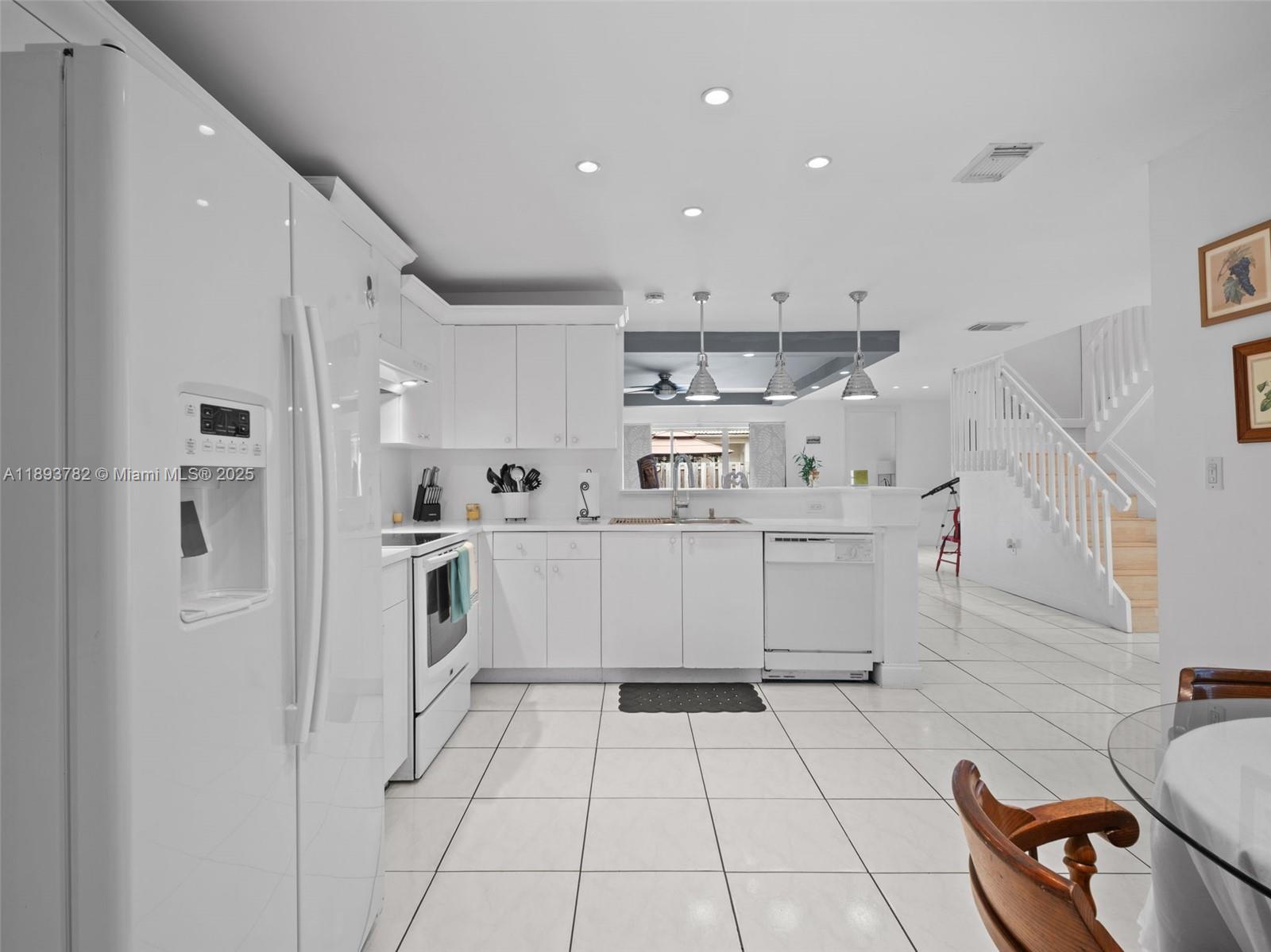 7486 Southwest 162nd Court Miami, FL 33193 - Photo 26 of 47 a kitchen with a sink a stove a refrigerator and white cabinets