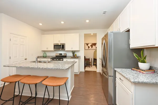 a kitchen with stainless steel appliances granite countertop a stove a refrigerator a sink and a dining table with wooden floor